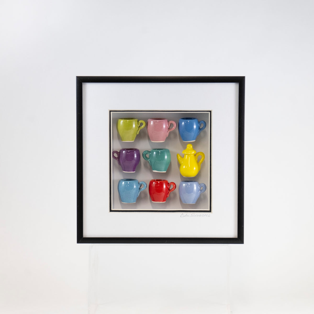 8x8 Shadowbox With a Yellow Teapot and Green, Teal, and Periwinkle Mugs in a Black Frame