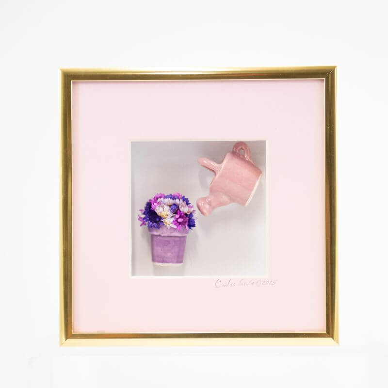 6x6 Shadowbox with a Pink Watering Can Pouring into a Purple Flower Pot in a Gold Frame