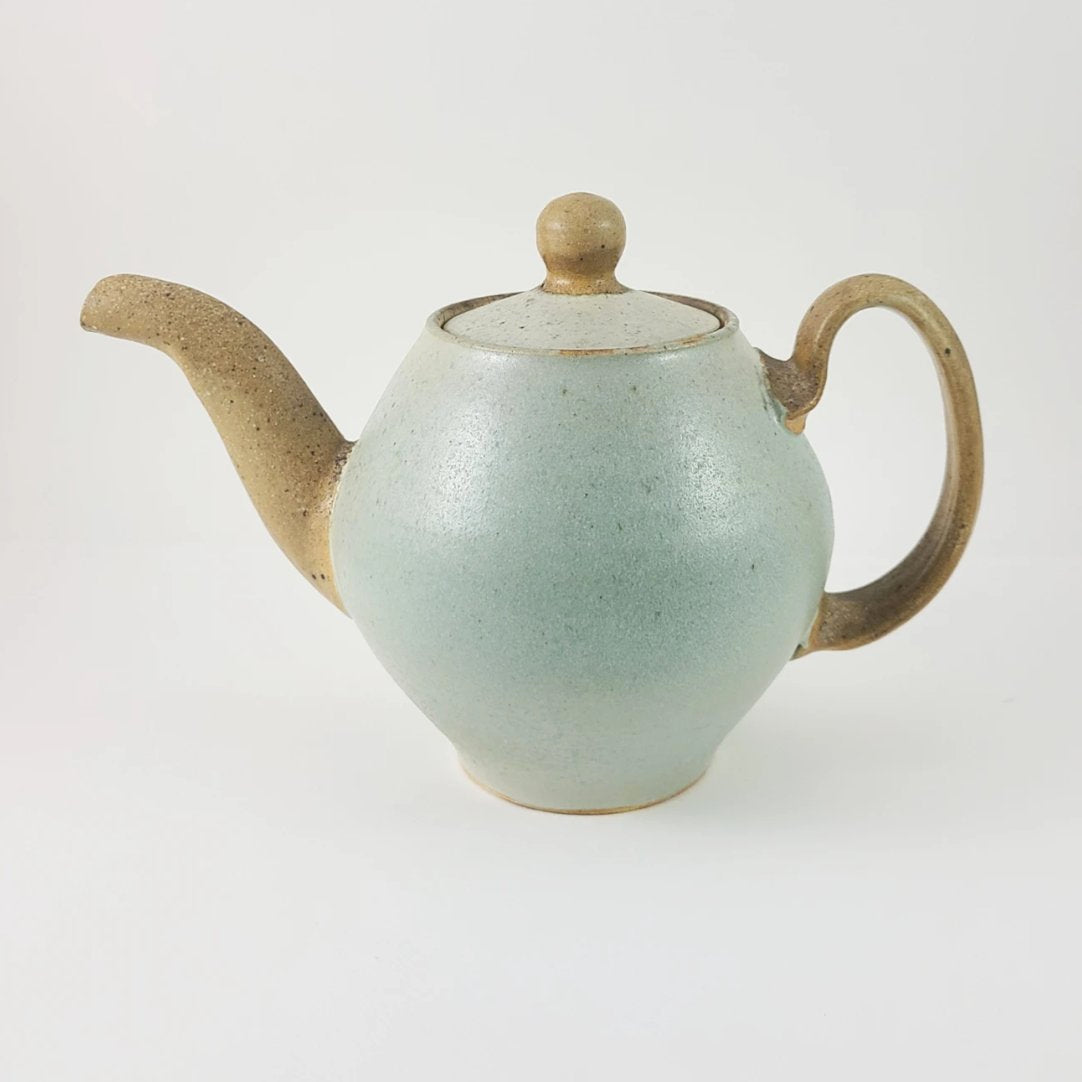Ceramic teapot with a light blue body, brown spout, handle, and lid knob on a white background.