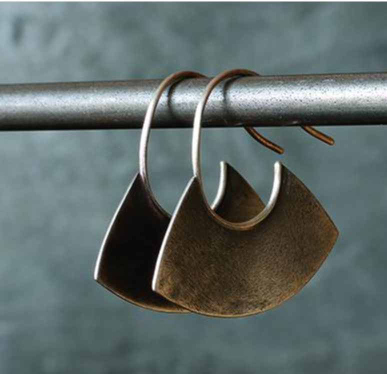 Bronze crescent-shaped earrings hanging on a metal rod against a textured gray background.