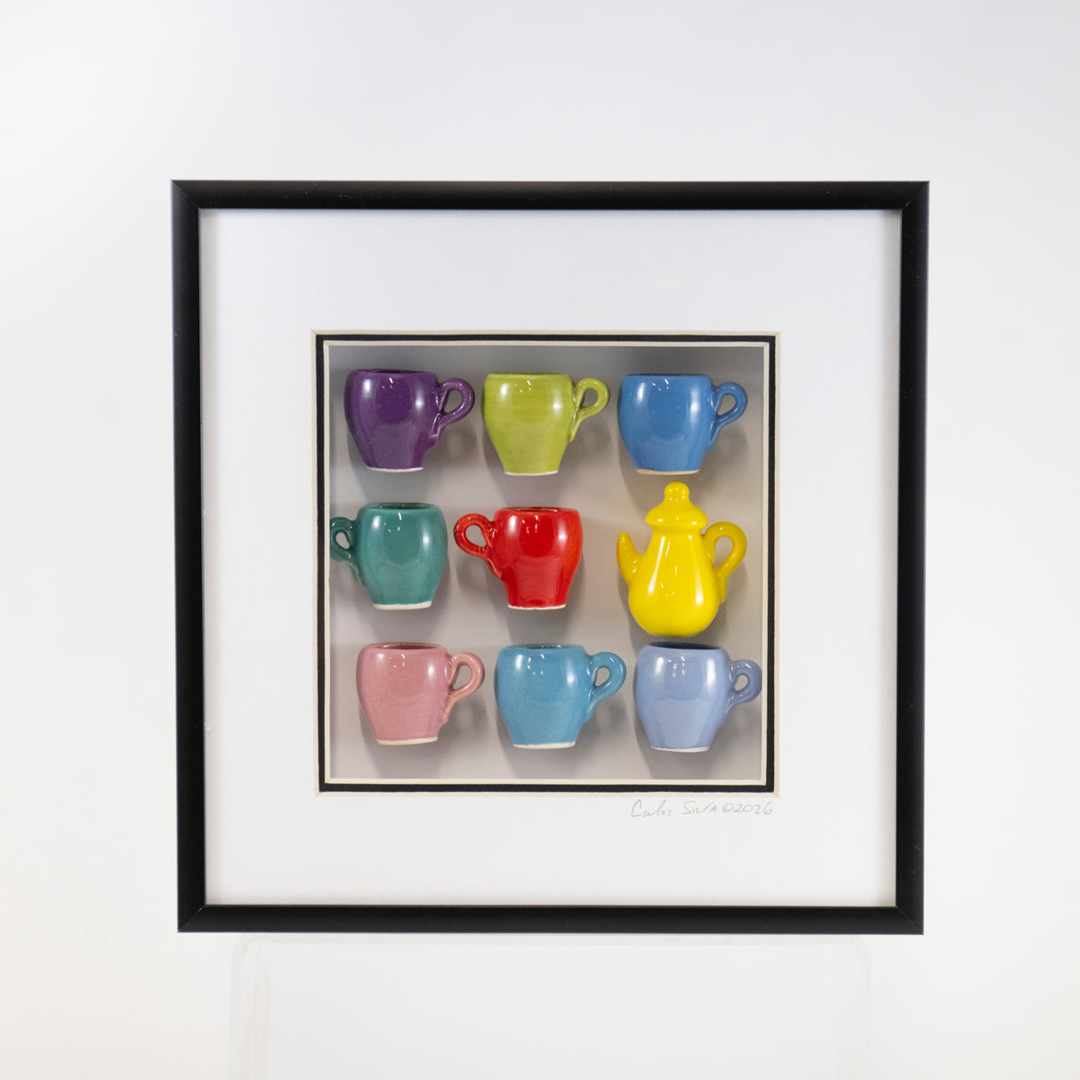 8x8 Shadowbox With a Yellow Teapot and Purple, Red, and Periwinkle Mugs in a Black Frame